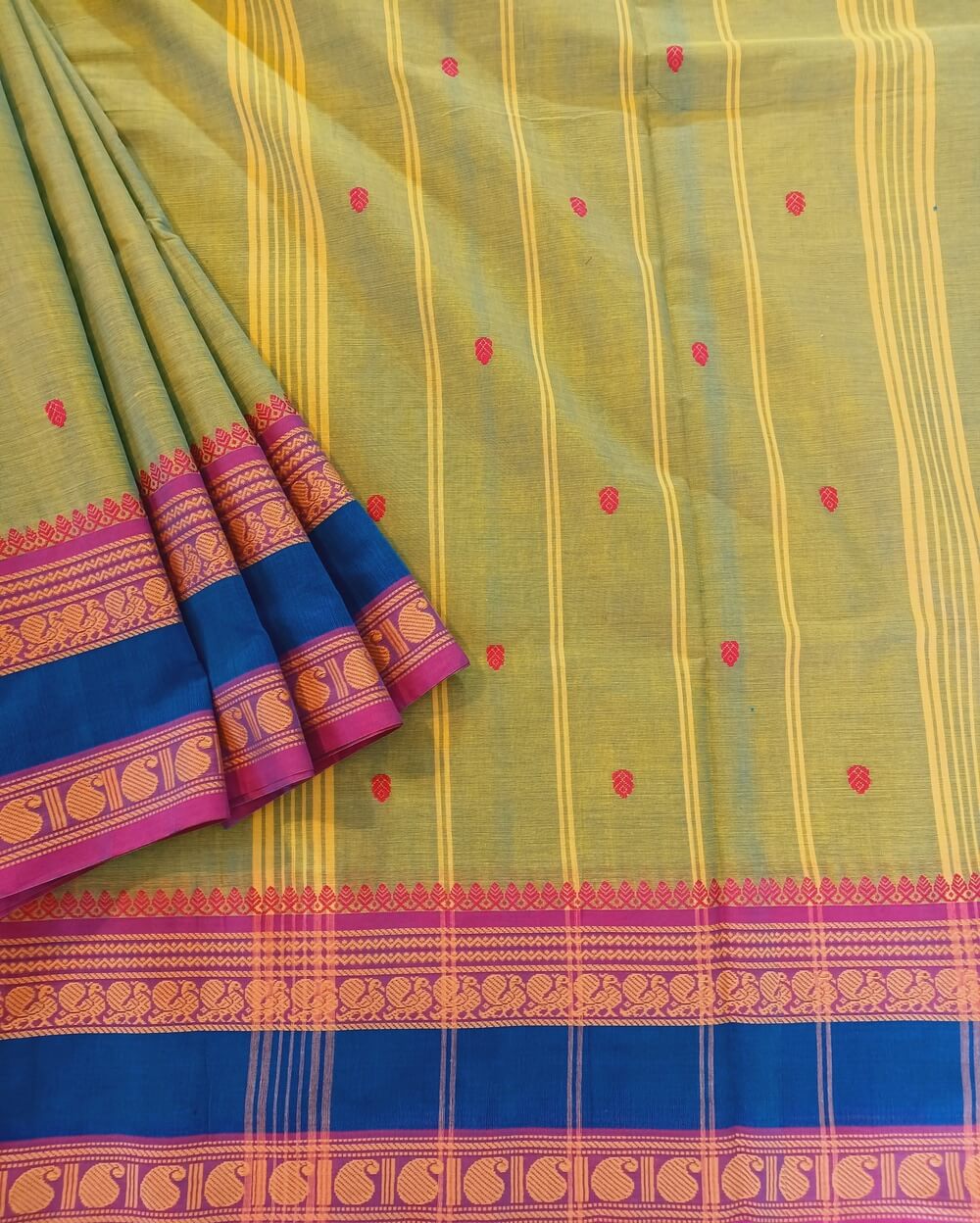 Kanchi Cotton Saree in Light Green and Blue dual tone shade. It has Buttas on Saree with Thread Border of traditional Peacock and Mango Motifs.