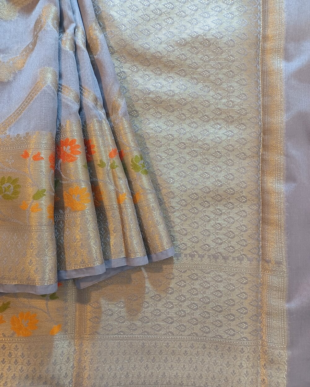 Georgette Saree in Greyish Blue Shade with Silver zari weaves in the famous Banarasi Jaal work. Border- has Banarasi floral motifs with Meena work,