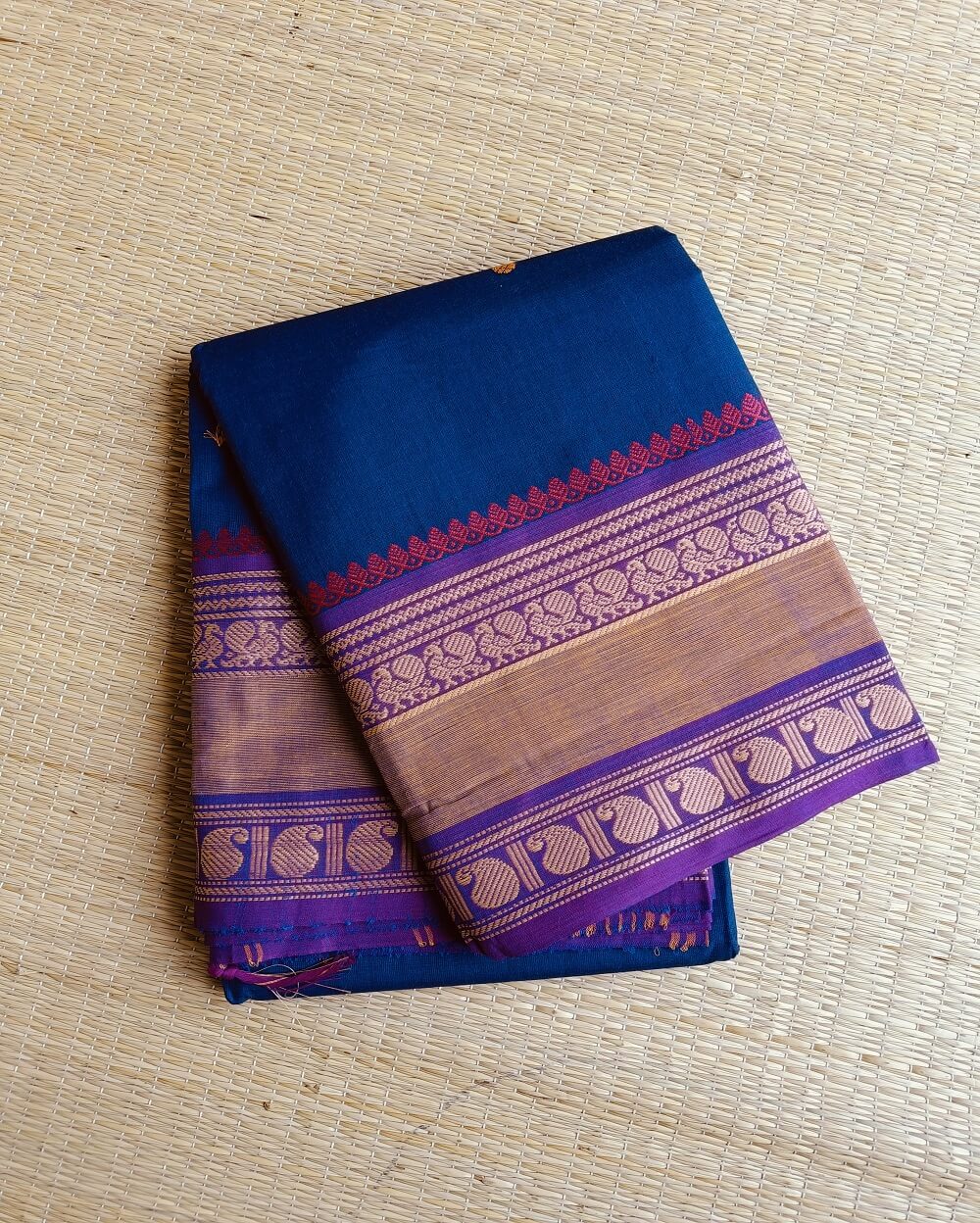 Handloom Kanchi Cotton Saree in Pleasant Shankhpushpi flower Blue with Purple border, it has Buttas on Saree and Thread Border with traditional Peacock and Mango Motifs.
