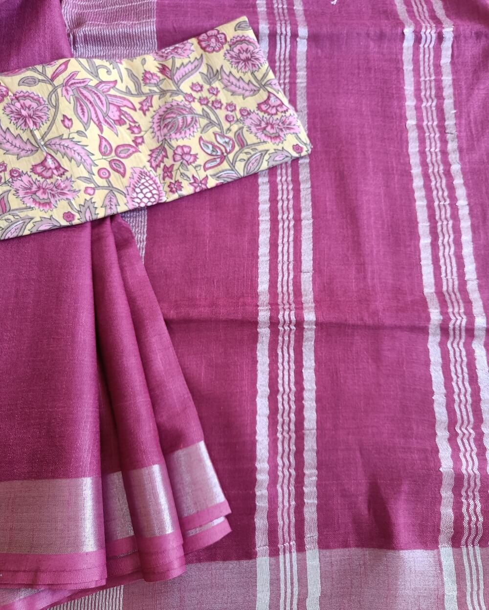 Dark Pink linen saree with silver tissue zari border and a light yellow handcrafted - hand block printed mul mul cotton blouse piece, The Linen saree comes comes with a plain body in very soothing shade with a subtle silver tissue zari border. The pallu is simple with silver stripes. The blouse piece is running blouse piece that comes along with saree and the additional one is a beautiful hand block printed