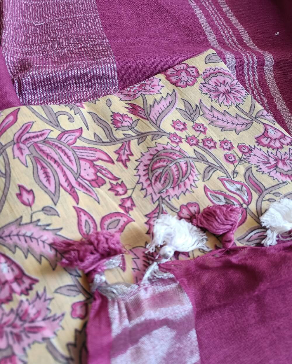Dark Pink linen saree with silver tissue zari border and a light yellow handcrafted - hand block printed mul mul cotton blouse piece, The Linen saree comes comes with a plain body in very soothing shade with a subtle silver tissue zari border. The pallu is simple with silver stripes. The blouse piece is running blouse piece that comes along with saree and the additional one is a beautiful hand block printed