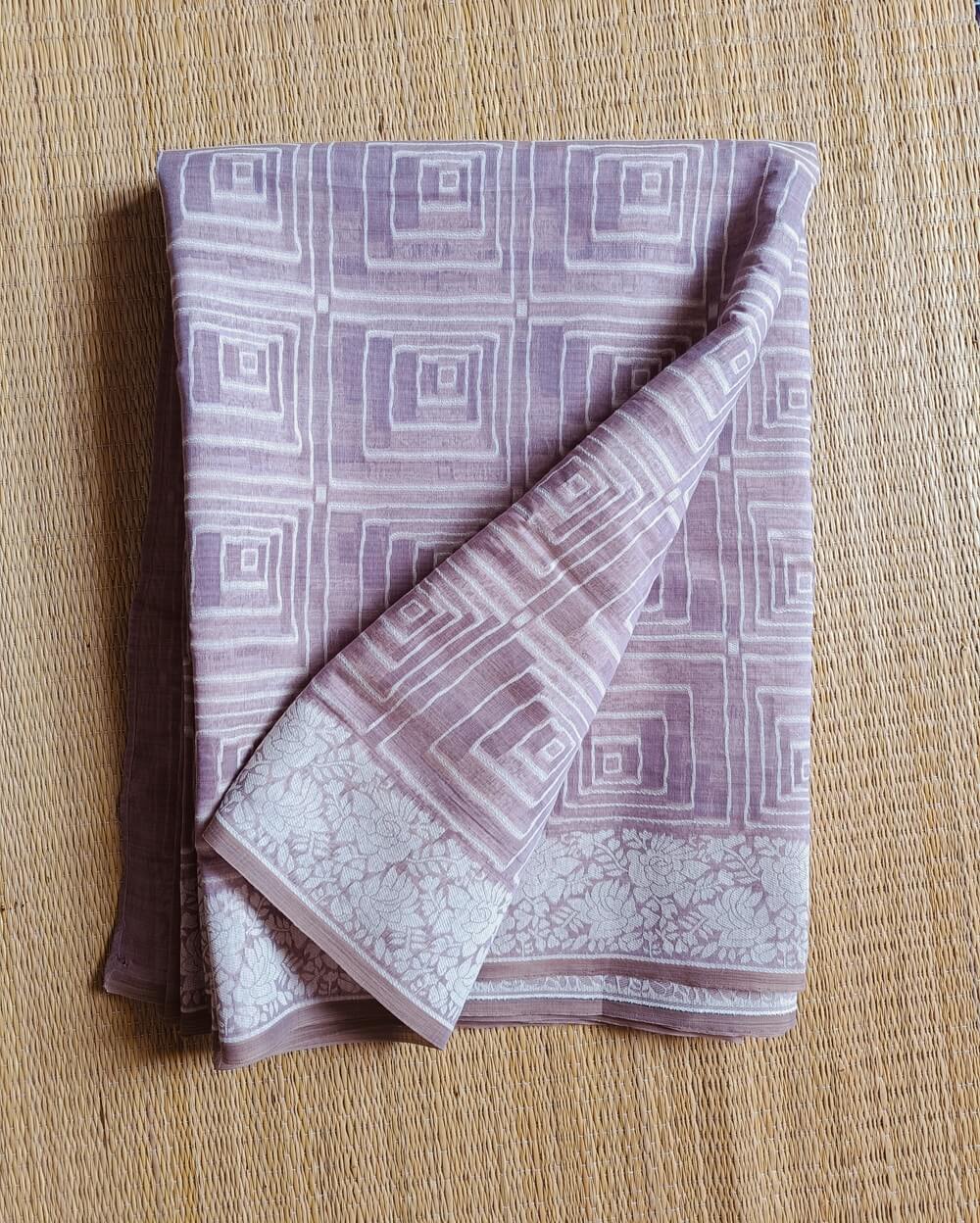 Light Lavender Linen saree with Mul Mul cotton fabric .This Linen saree has thread woven geometric square patterns all over the saree. The pallu is simple with a small line of zari woven . It's has beautiful floral border that compliments the over all unique look of the saree. The designs are very contemporary and exclusive.