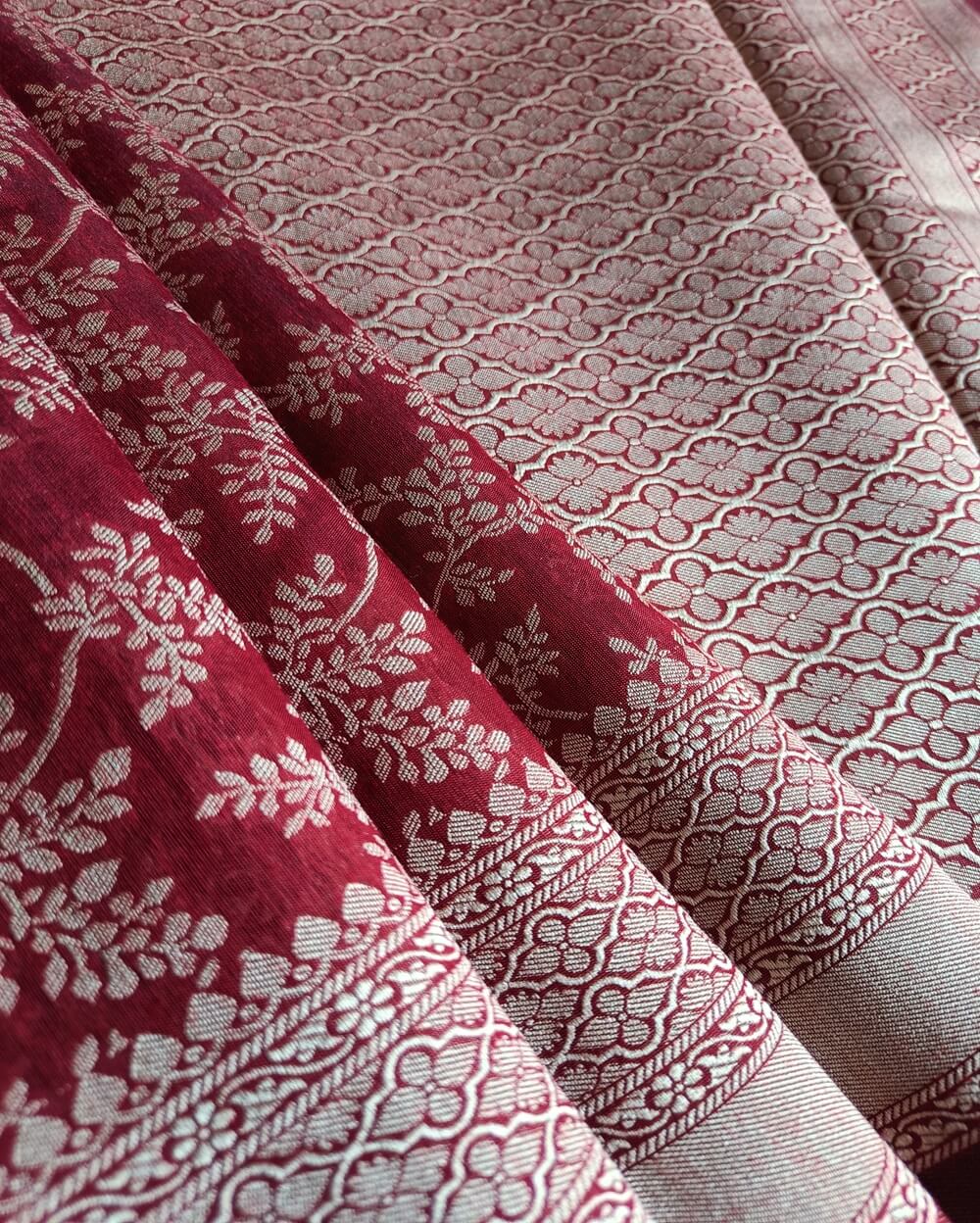 Banarasi Cotton Saree in Maroon colour with Cream resham threads woven all over. It has traditional Banarasi floral motifs in jaal weaves which is a very famous traditional weave where the motifs are interconnected throughout the saree.