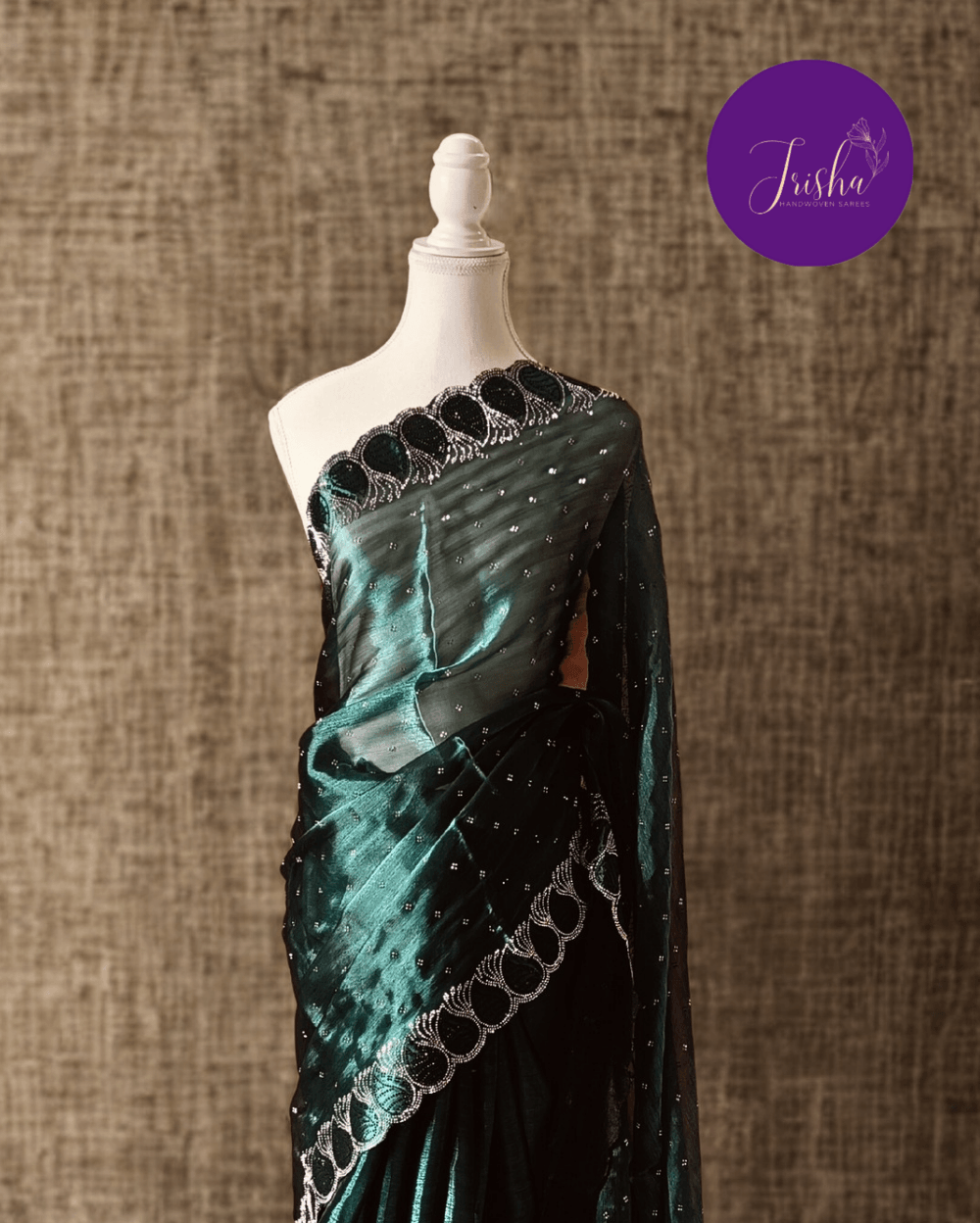 Jimmy Choo Organza silk saree in Dark Teal Green shade with black and white Swarovski crystal work in the border. The saree has Swarovski work on the shoulder part and the skirt portion of the saree in the form of small buttas. The Pallu is beautifully done in a C shape work pattern.