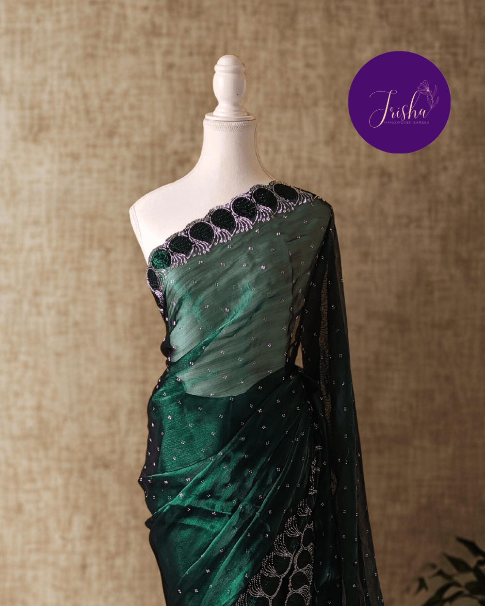Jimmy Choo Organza silk saree in Emerald Green shade with black and white Swarovski crystal work in the border. The saree has Swarovski work on the shoulder part and the skirt portion of the saree in the form of small buttas. The Pallu is beautifully done in a C shape work pattern.