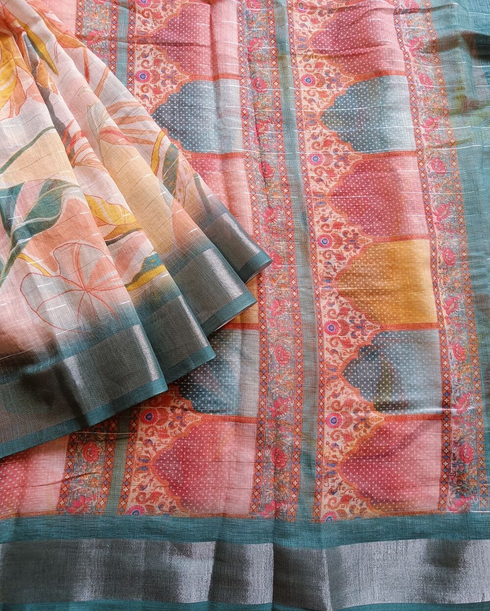 Teal Blue shade Semi Linen saree with silver tissue zari border, this saree comes with digital prints all over with a subtle silver tissue zari border. The pallu is simple with prints.
