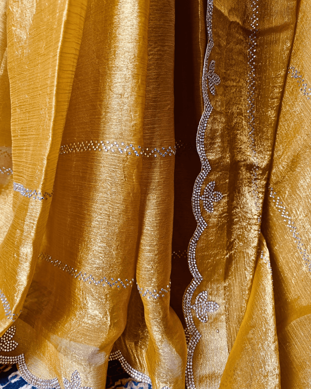 Golden Yellow fendy silk saree with Swarovski crystal work all over the shoulder and pallu portion in stripes pattern. Border throughout the saree and Pallu has diamond stone work .The saree in the skirt portion has 2 lines of striped Swarovski crystal work. The Pallu is beautifully done in a C shape work pattern. The shade has a light dual tone effect. Blouse piece has back design in Swarovski crystal work and sleeves potion has diamond stone work done.