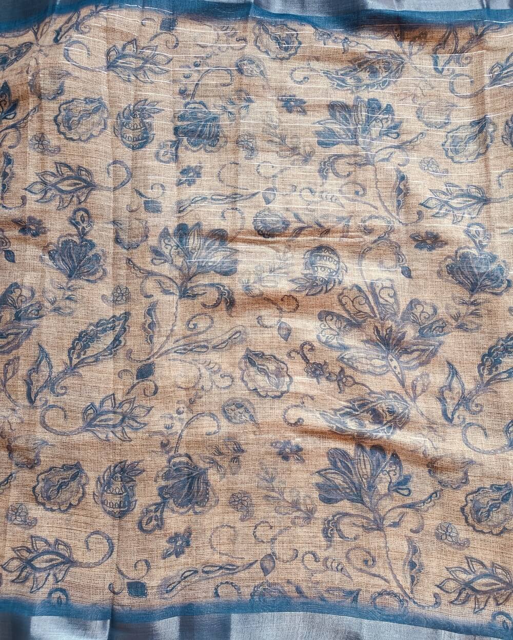 Jute Blue shade Semi Linen saree with silver tissue zari border, this saree comes with digital prints all over with a subtle silver tissue zari border. The pallu is simple with prints.