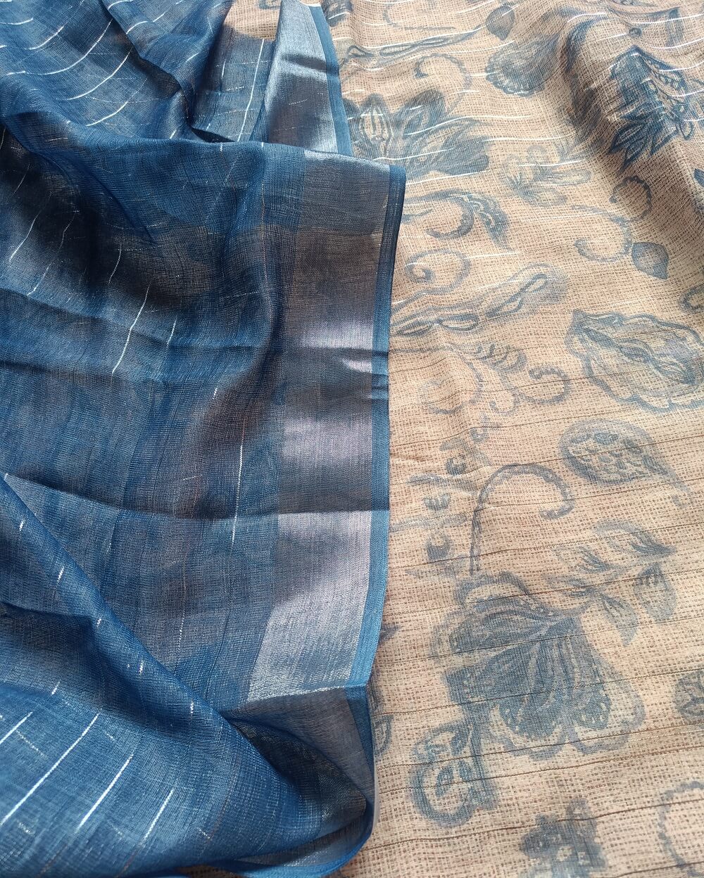 Jute Blue shade Semi Linen saree with silver tissue zari border, this saree comes with digital prints all over with a subtle silver tissue zari border. The pallu is simple with prints.