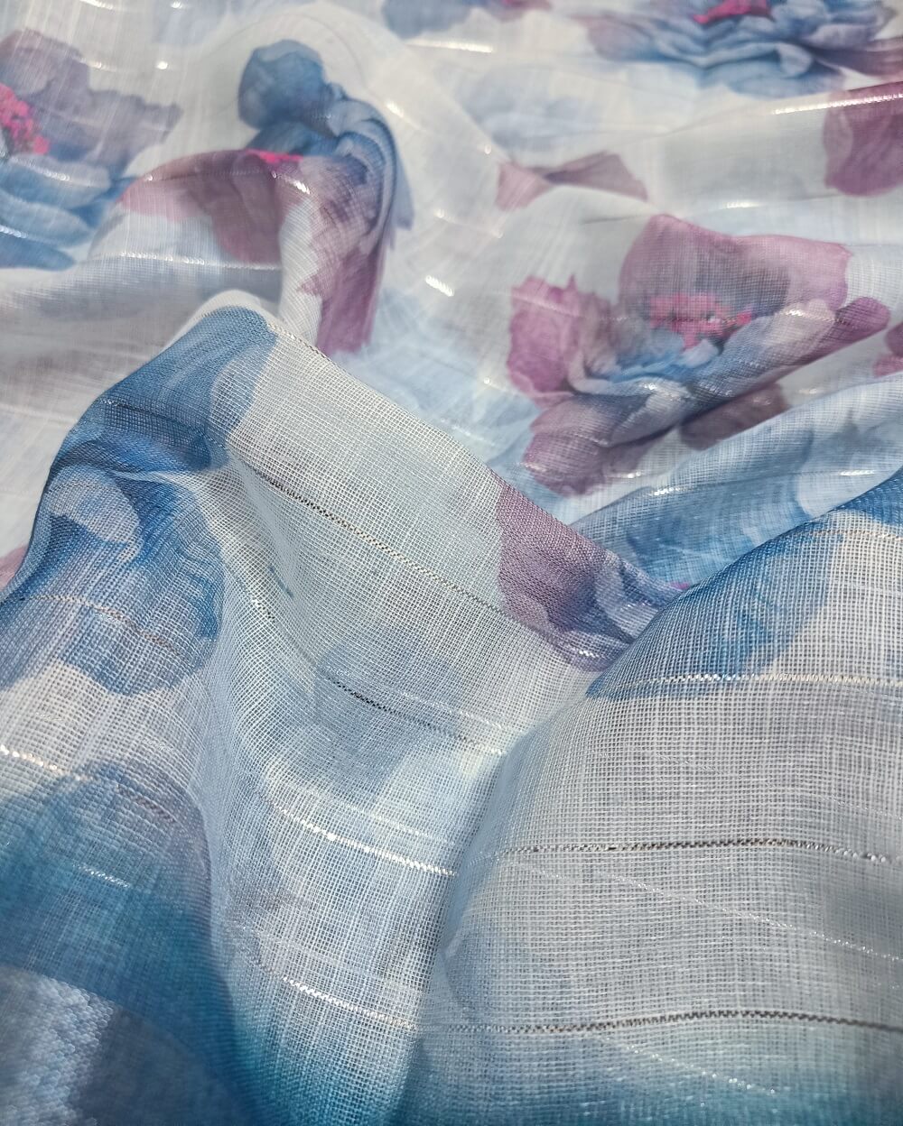 Sky Blue shade Semi Linen saree with silver tissue zari border, this saree comes with digital prints all over with a subtle silver tissue zari border. The pallu is simple with prints.