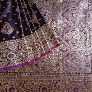 Banarasi Satin silk saree in Dark Wine Purple shade dual tone with floral motifs in light gold zari weaves all over the body. Very unique meenakari work done on the motifs in the base fabric shade. It has a self border with gold work floral motifs. The Pallu is richly woven with intricate Banarasi floral motifs. Meenakari work has been done In the border and pallu that compliments the whole look of the saree. It includes self embossed blouse piece with gold border in same design as the saree.