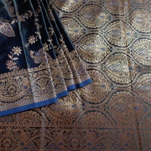 Banarasi Satin silk saree in Dark Royal Blue shade dual tone with peacock and creeper motifs in light gold zari weaves all over the body. Very unique meenakari work done on the motifs in the base fabric shade. It has been woven in the most famous jaal weaves i.e. All the motifs are connected throughout the saree. It has a self border with gold work floral and peacock motifs. The Pallu is richly woven with intricate Banarasi floral motifs. Meenakari work has been done In the border and pallu that compliments the whole look of the saree. It includes self embossed blouse piece with gold border in same design as the saree.
