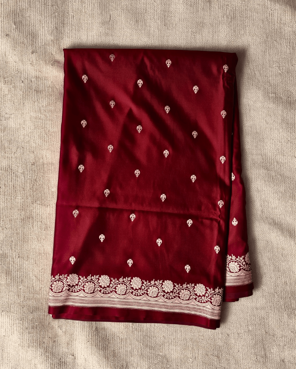 Banarasi Mashru Katan Silk saree in Deep Maroon with small buttis all over the saree. The Rose Gold zari makes the finish very royal and elegant. Saree has a very beautiful traditional border and a very rich pallu that makes the usage of this saree suit any occasion or formal wear. The Pallu is attractively designed and woven with intricate Banarasi floral motifs.