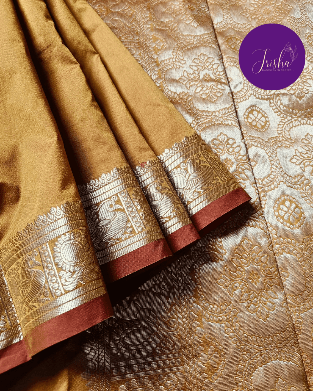 Kanchipuram / Kanjivaram Silk Saree with Gold Zari Border on both sides with traditional Kanchipuram Peacock motifs. Mustard Yellow dual tone with Brick Red selvedge saree with Self Border and Pallu. Traditional Peacock motifs in the border with floral motifs all over pallu. Body of the saree has small floral buttas in two different geometric patterns.